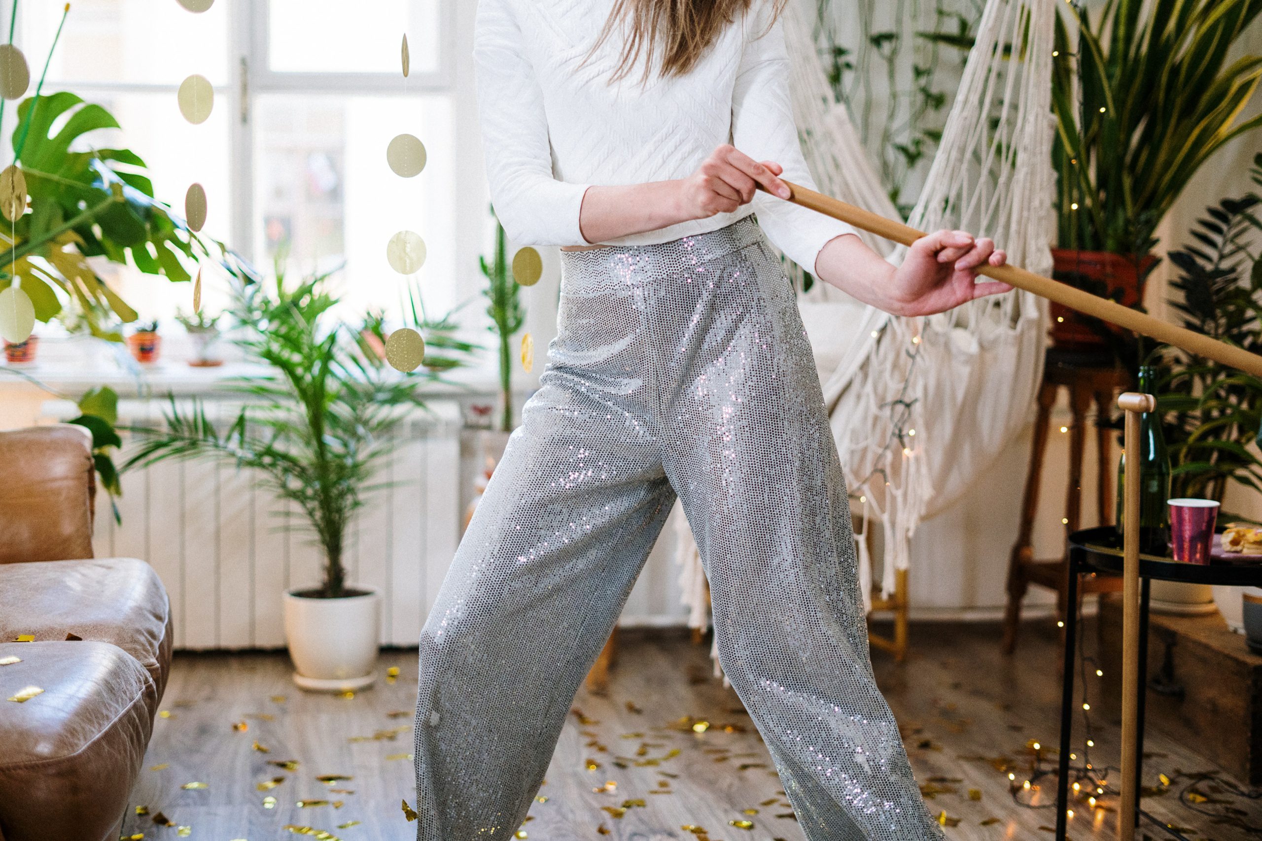 Woman in disco ball pants dances while she cleans her apartment