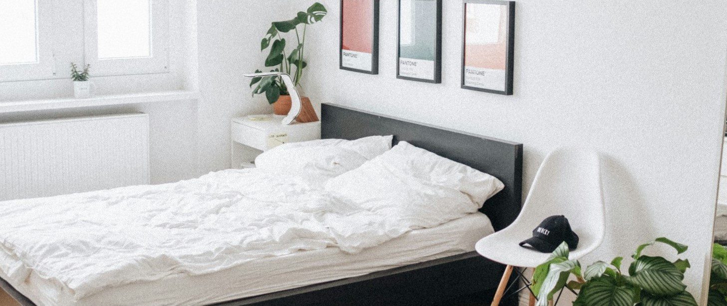 clean, minimalist bedroom ideal for sleep with plants, wall fixtures and a mirror
