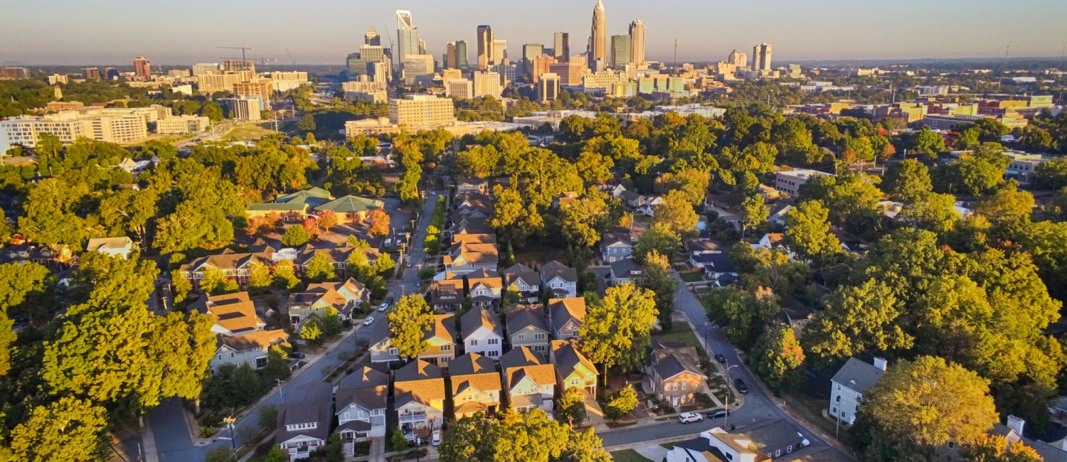Drone view of the sun setting over the Charlotte skyline as seen from the surrounding suburbs